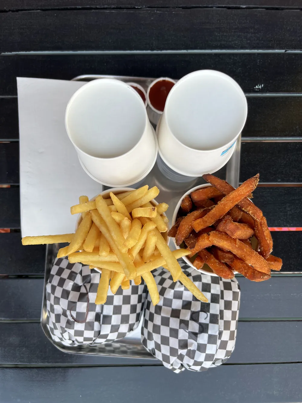 Tray of burgers in checkered boxes with fries, seen from above